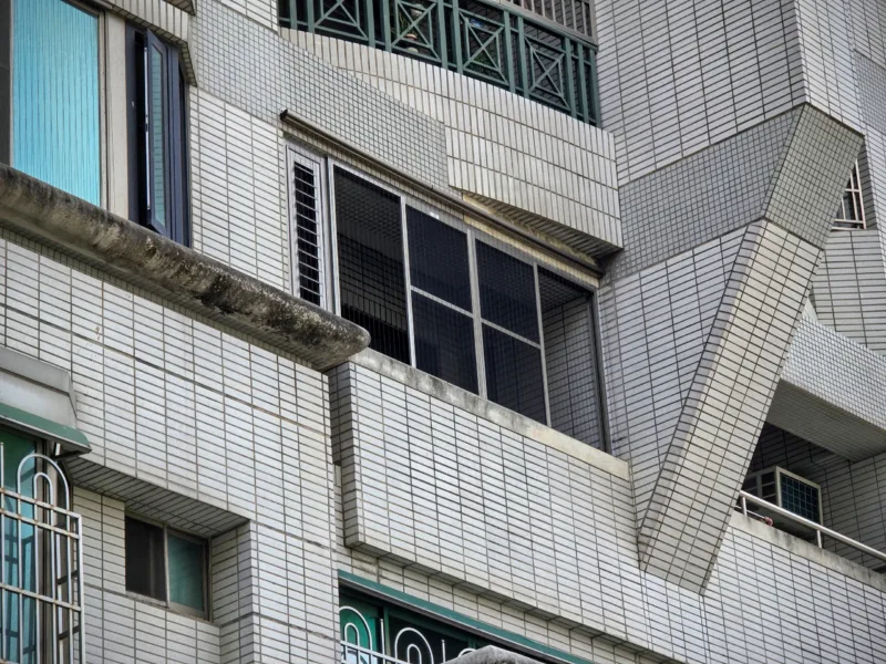公寓大樓前陽台外觀實景:安裝大型四拉窗搭配側邊活動百葉窗,完美融入大樓磁磚外牆,兼顧採光與通風設計。