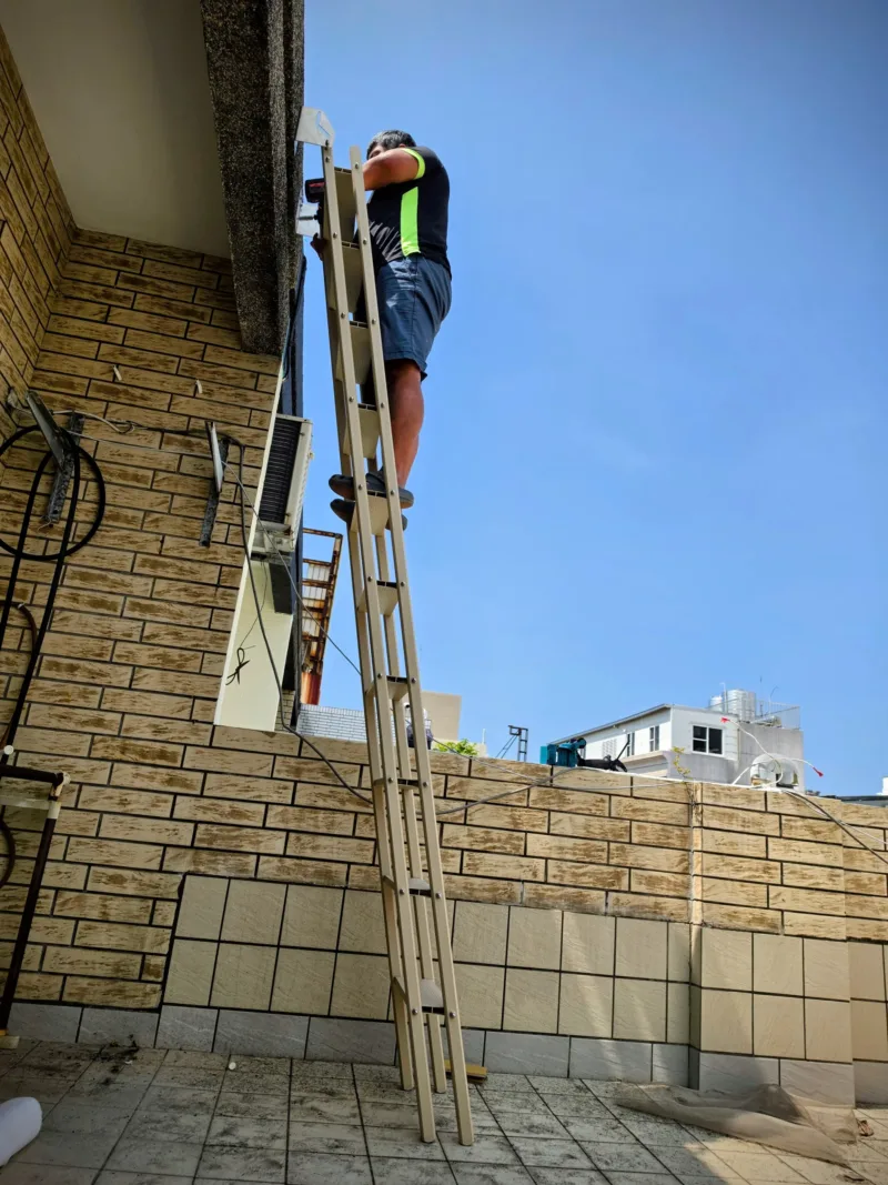 好室科技師傅安穩站在佛斯特爬梯的寬版平坦踏階上進行鑽孔作業,完美示範梯身結構的極致穩定性。